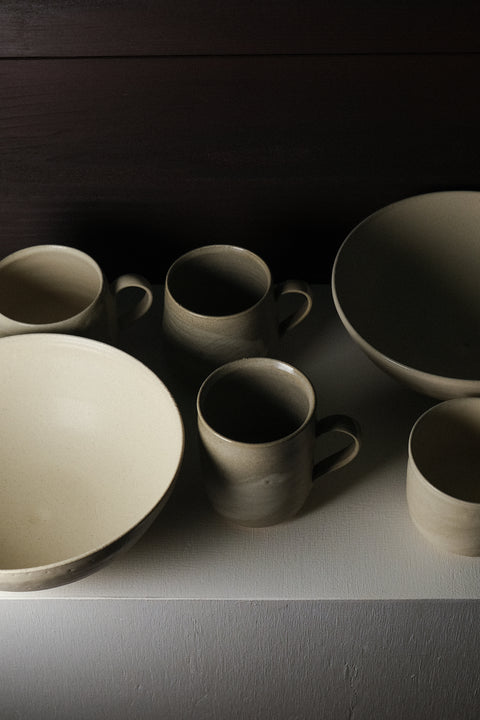 Set of ceramic bowls and mugs on a dark surface